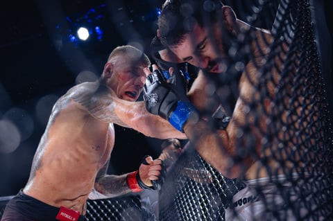 Two MMA fighters in combat inside an octagon cage during a professional mixed martial arts match