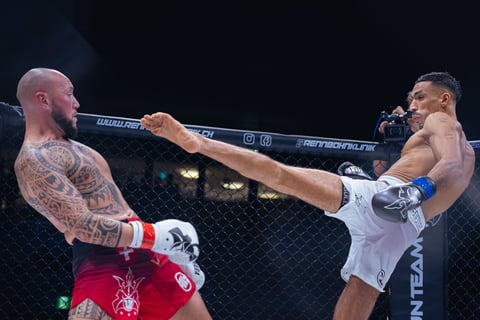 MMA fighter delivering a high kick to opponent inside octagon cage during professional mixed martial arts match
