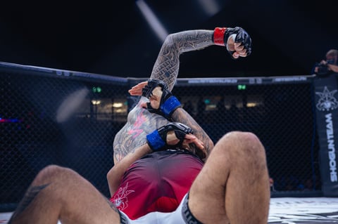 MMA fighter performing an aerial move over opponent in octagon cage during professional mixed martial arts competition